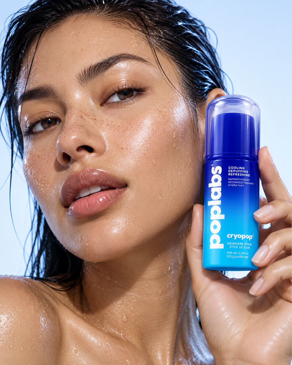 Woman with dewy skin holding the CRYOPOP cooling stick to her cheek