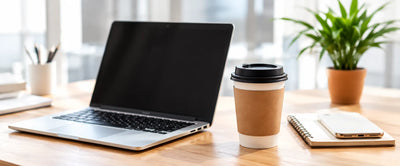 Desk with an open laptop, coffee cup and notebook